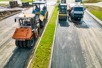 Asphalt laying equipment. Asphalt paver machine on the road repair site. Road renewal process, construction work. View from above. Drone photography.