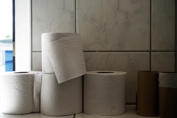 Badezimmer mit geöffnetem Fenster, weißen Wandkacheln mit Muster und Ablage mit KLopapierrollen 