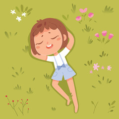 Cute child lying on green grass of summer park with lawn or playground, top view