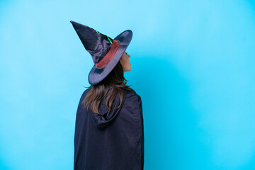 Young hispanic woman dressed as witch over isolated background in back position and looking back