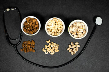 Obraz na płótnie Canvas Healthy Foods concept. Mixed nuts in bowls with stethoscope with nuts for diet. Different kinds of tasty and healthy nuts