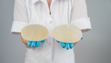 Doctor plastic surgeon demonstrates different breast implants. 