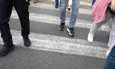 Zebra crossing. Legs of a crowd of busy pedestrians crossing a street.