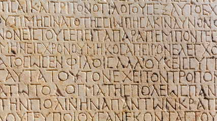 Historical inscription. Fragment of ancient greek text, carved on marble block at the archaeological site of Ephesus. Selcuk, Turkey (Turkiye). Ancient art and history concept. Retro background
