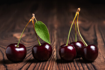 Sweet cherries with cherry leaf on a wooden background.