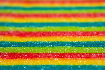 Background of rainbow sour jelly candies strips in sugar sprinkle. Top view, copy space