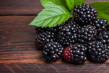 Blackberries with leaves on wooden background close up