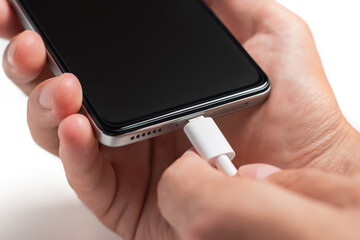 Man hands plugging a charger in a smart phone. Man using smartphone with powerbank.