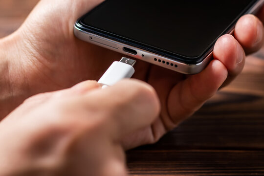 Man Hands Plugging A Charger In A Smart Phone. Man Using Smartphone With Powerbank.