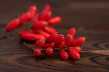 Barberry, Berberis vulgaris, branch with natural fresh ripe red berries on wooden background.