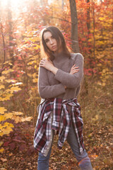Beautiful young woman posing in autumn forest under sunlight