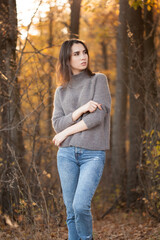 Beautiful woman posing in yellow autumn forest under sunlight