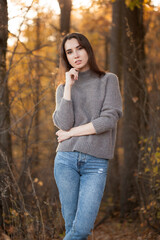 Beautiful young woman posing in yellow autumn forest under sunlight