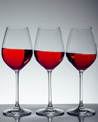 Series of three glasses of wine on gray background