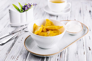 Yellow dumplings with sour cream on a plate closeup