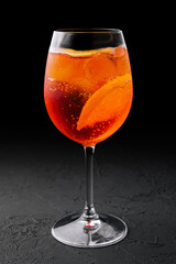 glass of aperol spritz cocktail on black background