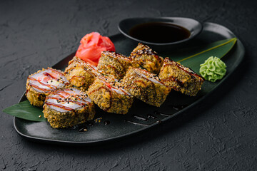 Served warm sushi with ginger and wasabi on a black stone plate