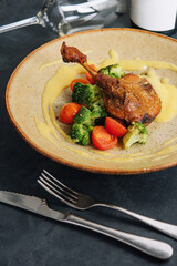 Confit duck leg with broccoli and tomatoes