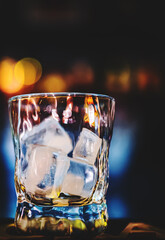 Ice cube in an empty glass on a bar counter in bar or pub
