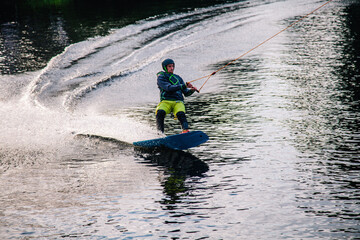 A guy in a yak suit at sunset jumps from a springboard on a wakeboard in an extreme park in Kiev. Ukraine.