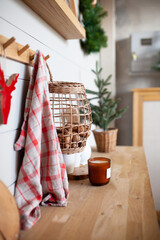 Details of modern christmas kitchen interior. Wicker basket with walnuts, candle, towel, deer decoration, christmas tree. Scandinavian style. Home improvement.  Vertical image. Selective focus.