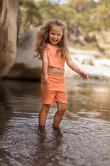 little girl and a splash of water.  smiling child. a girl with flowing hair by the water. Little girl playing on the shore