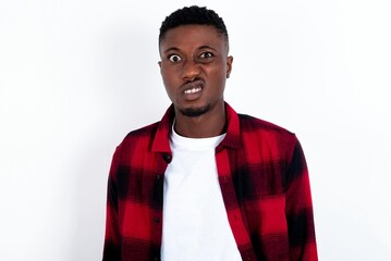 Portrait of dissatisfied young handsome man wearing overshirt over white background smirks face,...