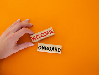 Welcome onboard symbol. Concept words Welcome onboard on wooden blocks. Beautiful orange background. Businessman hand. Business and Welcome onboard concept. Copy space.