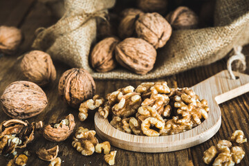 Whole and peeled walnuts on a rustic wooden table, focus on the walnut kernels