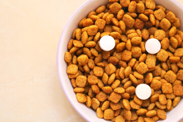 Cat food with three pills in a bowl on the floor. Vitamins for cats. Cat treatment