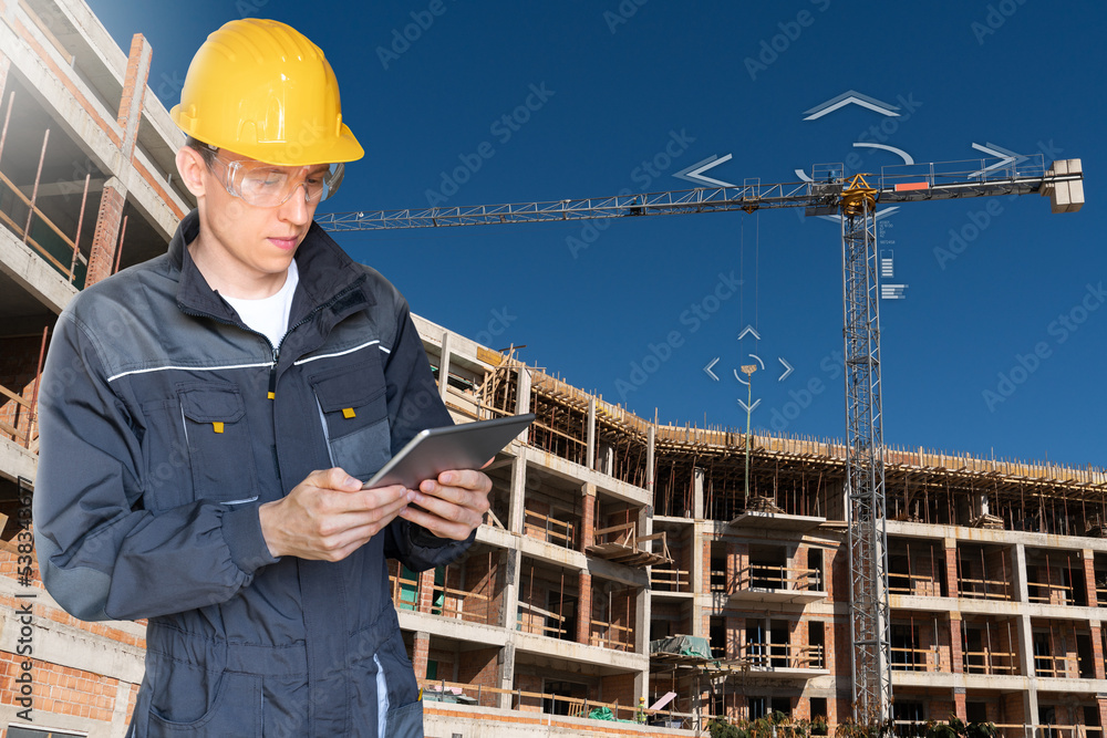 Poster Builder with a digital tablet controls a remote-controlled unmanned crane. Digital transformation in construction industry.	