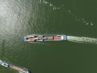 Top down view of an inland transportation vessel for container shipping and logistics distribution. Ship loaded with containers and merchandise for commercial and international transport. Aerial