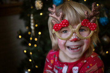 Smiling happy child in a festive make-up of a deer. The kid is waiting for a miracle. Christmas,...