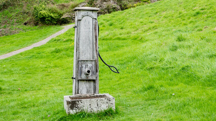 Old wooden hand operated water pump and stone trough