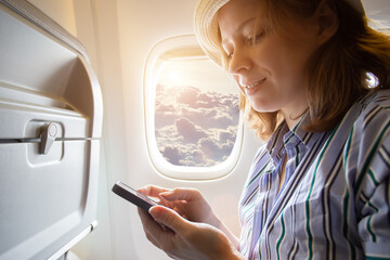 passenger inside the plane, a tourist with a smartphone on the passenger seat book a hotel room...