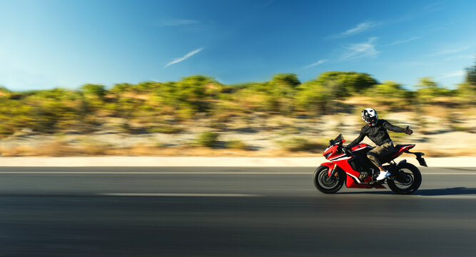 Side view of a motorcycle rider riding red race motorcycle on the highway with motion blur. © ardasavasciogullari
