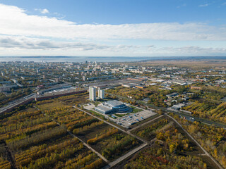 Aerial panorama of the city on the riverbank. A river near the city in the warm light of sunrise. Bird's-eye view. Aerial photography. A picture from a drone.