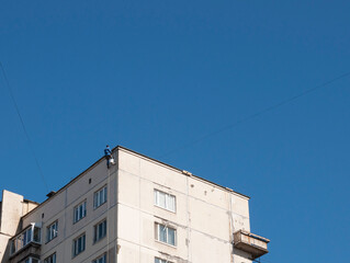 A working industrial climber hangs from the roof of the house sealing the seams between the panels
