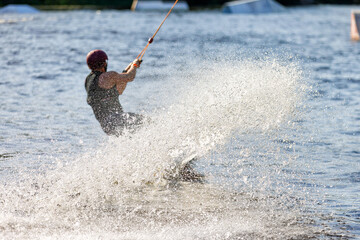 Splash of silver water splashes after a wakeboarder's sharp turn on the water surface of a river.