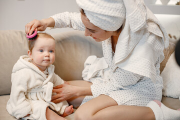 Charming mother and little baby daughter with hair wrapped in towels