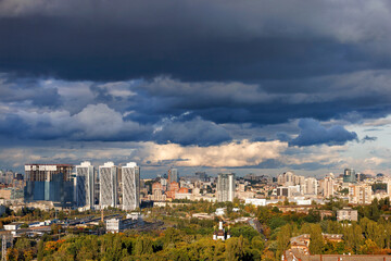 Thunderclouds over the city illuminated by the rays of the evening sun. Beautiful cityscape from a bird's eye view.