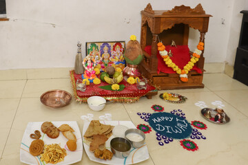 Diwali pooja arrangement with rangoli and prasad offering.