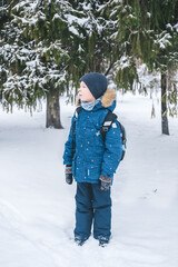 Fototapeta na wymiar boy in a jacket, stands on the street in winter. Schoolboy on the street in winter. Lost Lonely Child Snowy Street 