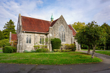 Fototapeta na wymiar old English church surrounded by greenery. traditional stone chapel in city cemetery 