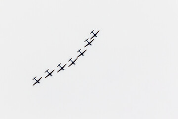 Silhouette of seven single engine planes flying lined up in the sky. Sports and leisure.