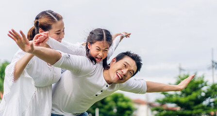 Portrait of enjoy happy love asian family father and mother holding hug cute little asian girl child smiling play and having fun moments good time in summer park at home
