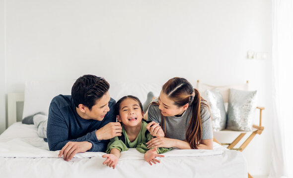 Portrait of enjoy happy love asian family father and mother holding hug cute little asian girl child smiling play and having fun moments good time in at home.