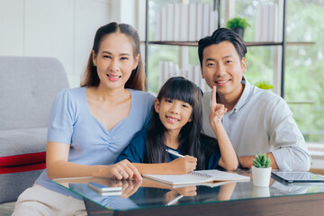 Cheerful asian parent dad and mom teaching daughter studying doing homework, Education concept