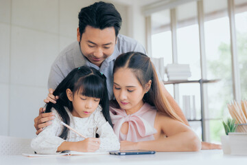 Attractive asian farther mother teaching little child daughter learning studying doing homework with digital tablet at home, Family education concept