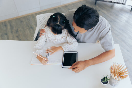 Attractive asian father teaching little child daughter learning studying doing homework at home, Family quality time and e-learning education concept